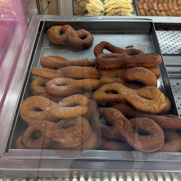 Bandeja met&aacute;lica llena de rosquillas reci&eacute;n fritas y azucaradas