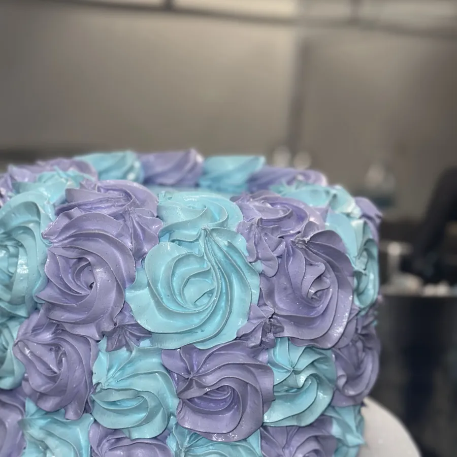 Cake decorado a mano con rosetas de merengue en lila y turquesa