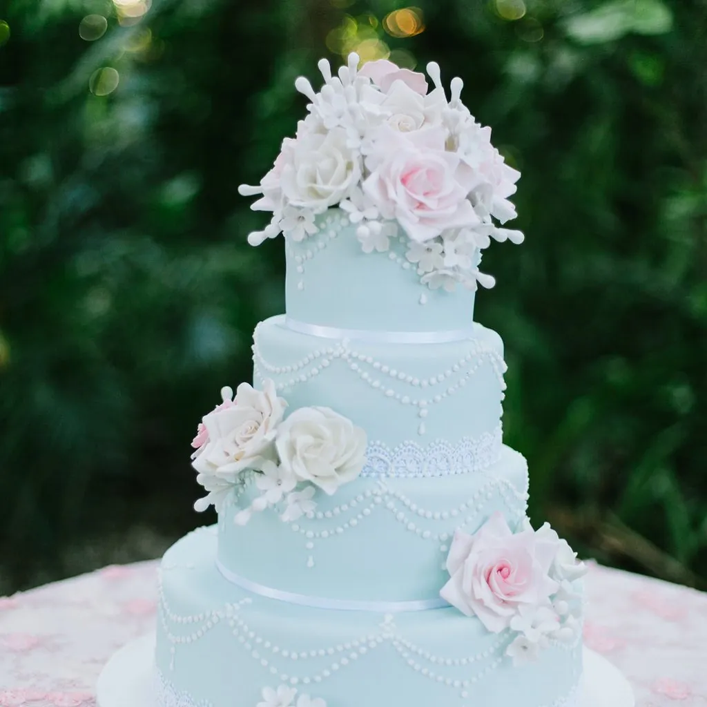 Tiered pale-blue wedding cake dressed with sugar roses