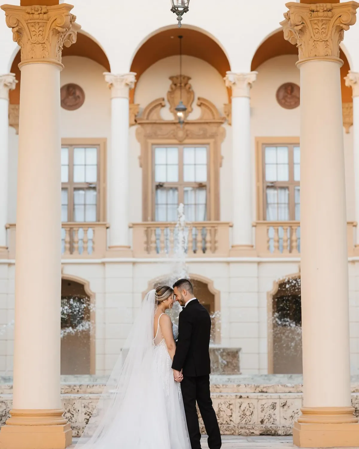 Couple photographed under the arches of a stone courtyard