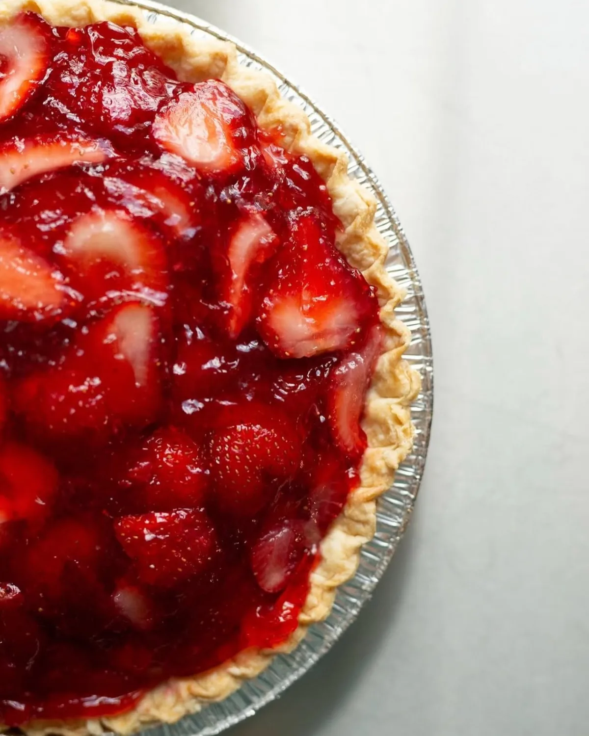 A strawberry pie covered in glazed fresh strawberries