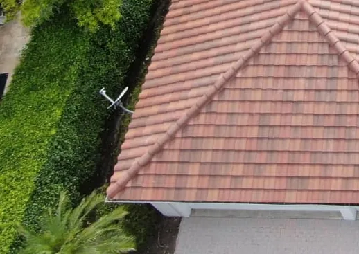 Clay tile roof on a hip roof house surrounded by trees.