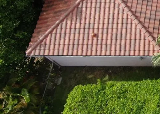 Clay tile roof finished on a house surrounded by hedges.