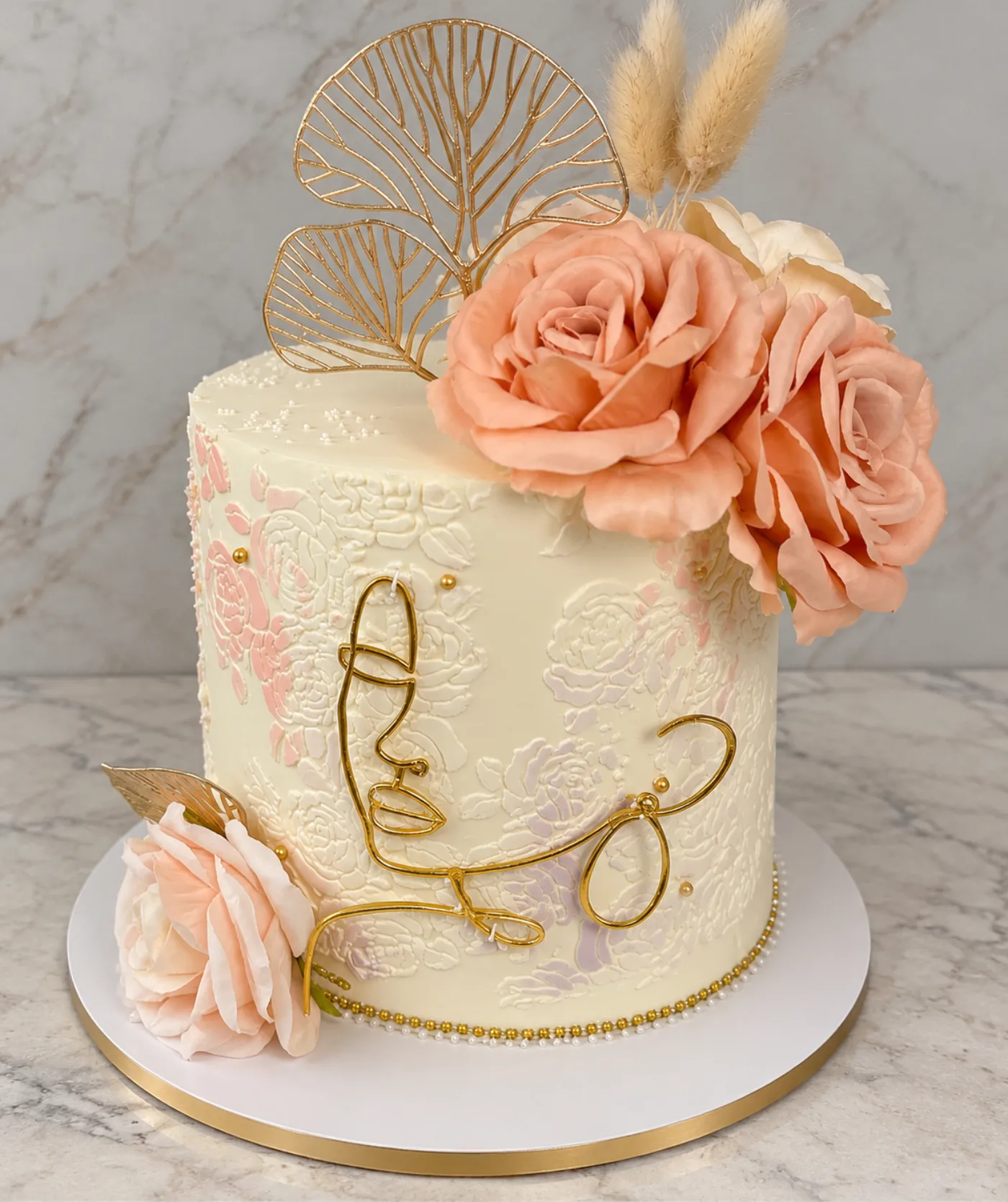 Cream cake with peach roses and gold leaf detail